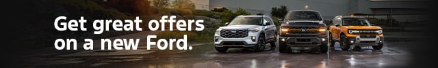 A range of Ford vehicles are parked in front of a Ford plant on rain-soaked asphalt under a cloudy sky at sundown, Text reads: Get great offers on a new Ford.